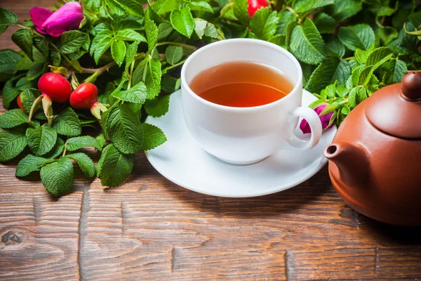 Chá saudável com uma rosa brava na mesa de madeira — Fotografia de Stock