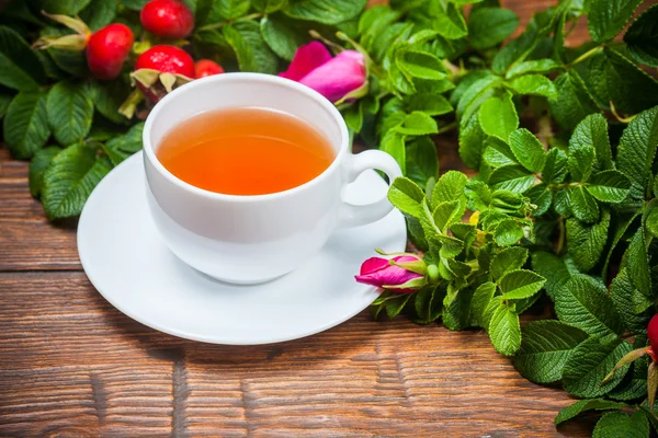 Chá saudável com uma rosa brava na mesa de madeira — Fotografia de Stock