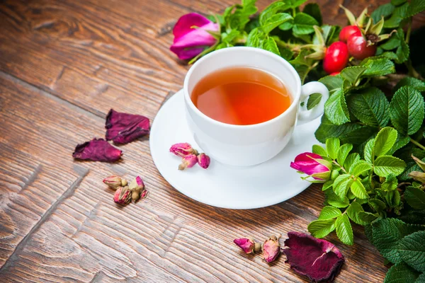 Chá saudável com uma rosa brava na mesa de madeira — Fotografia de Stock