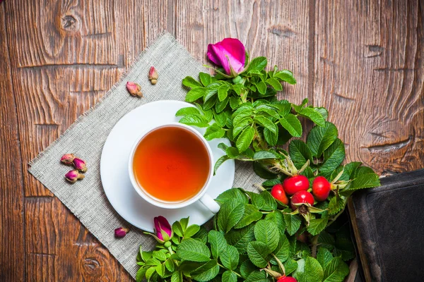 Gesunder Tee mit Heckenrose auf Holztisch — Stockfoto