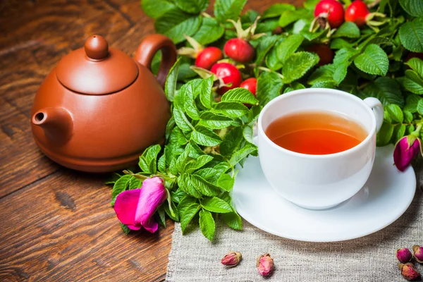 Gesunder Tee mit Heckenrose auf Holztisch — Stockfoto