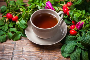 Ahşap masa üzerinde bir dogrose ile sağlıklı çay