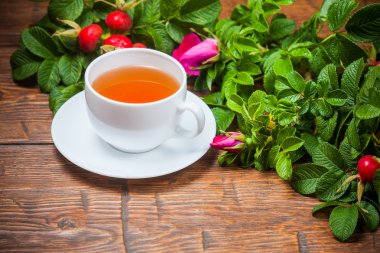 Ahşap masa üzerinde bir dogrose ile sağlıklı çay