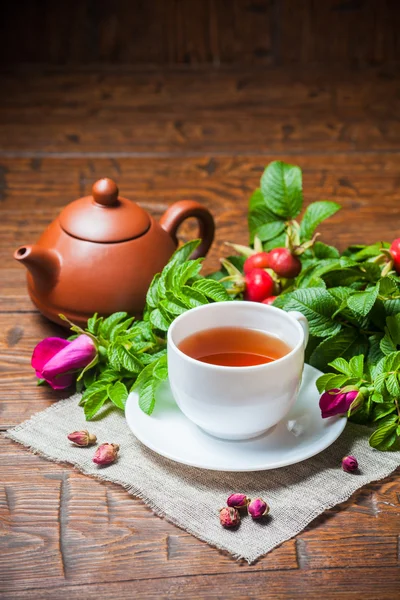 Gesunder Tee mit Heckenrose auf Holztisch — Stockfoto