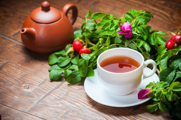 Gesunder Tee mit Heckenrose auf Holztisch — Stockfoto
