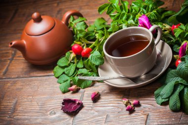 Ahşap masa üzerinde bir dogrose ile sağlıklı çay