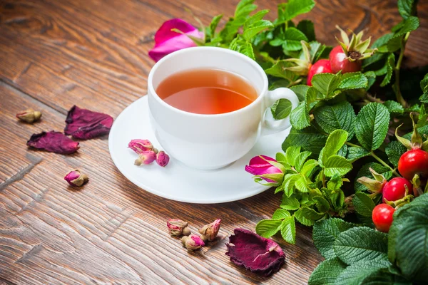 Gesunder Tee mit Heckenrose auf Holztisch — Stockfoto