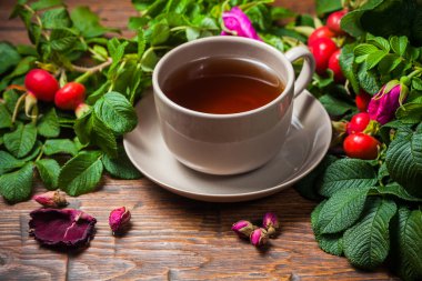 Ahşap masa üzerinde bir dogrose ile sağlıklı çay