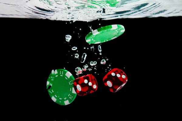 Red dice and chips in the water on black background — Stock Photo, Image