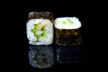 Geleneksel taze Japon suşisi siyah arka planda yuvarlanıyor.