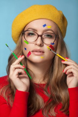 Portrait of a woman with colorful paint brushstroken on face. Bright green eyes.