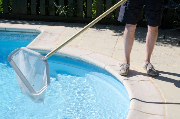 Hombre con una red limpiando una piscina —  Fotos de Stock