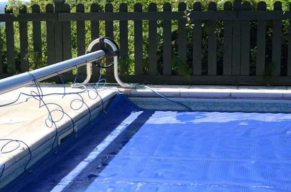 Swimming pool cover off its roller and covering the pool — Stock Photo, Image