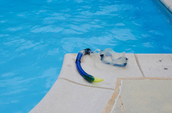 Esnórquel y máscara tumbados en las baldosas en el borde de una piscina —  Fotos de Stock