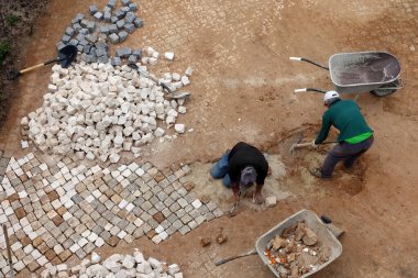 Sagres, Portekiz 15 Nisan 2019: Portekiz 'in ünlü geleneksel Calcada metodunu kullanarak asfalt bir alan inşa eden iki adama tepeden bakmak.