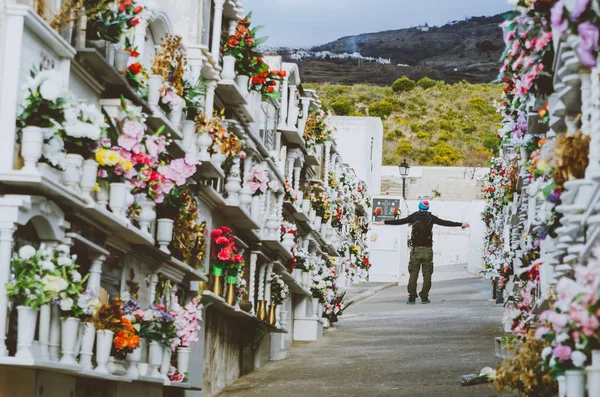 Kolları olan bir adam ayakta bir İspanyol tarzı mezarlık renkli çiçekler arasında sonundaki yaymak