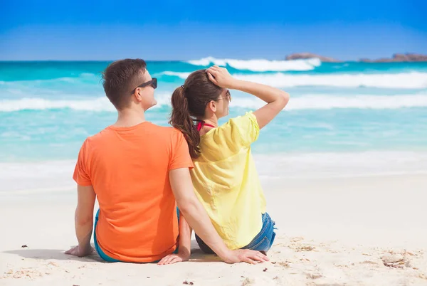 Vista para trás do jovem casal sentado na praia, Grand Anse, La Digue, Seychelles — Fotografia de Stock