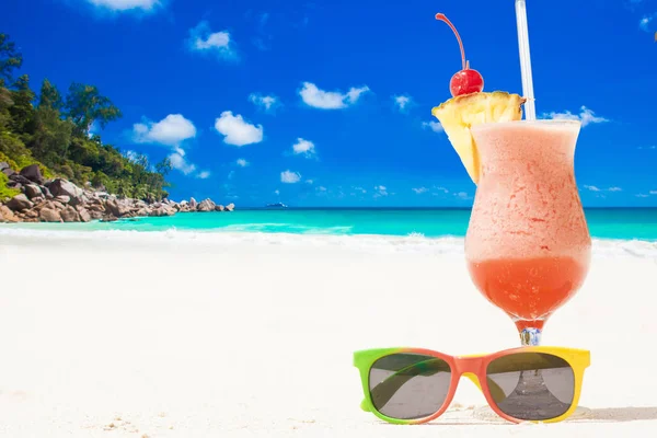 Bardak meyve kokteyli ve plaj tarafından güneş gözlüğü — Stok fotoğraf