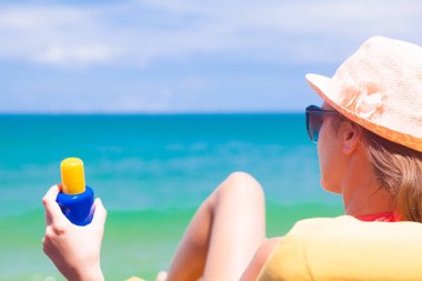kadın güneş koruyucu krem tutan o sahilde şezlong üzerinde rahatlatıcı