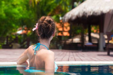 arkadan görünüşü lüks tropikal havuzunda rahatlatıcı bikinili kadın