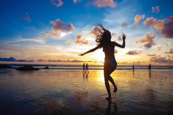 年轻合适的女人跳海边落日下的剪影 — 图库照片