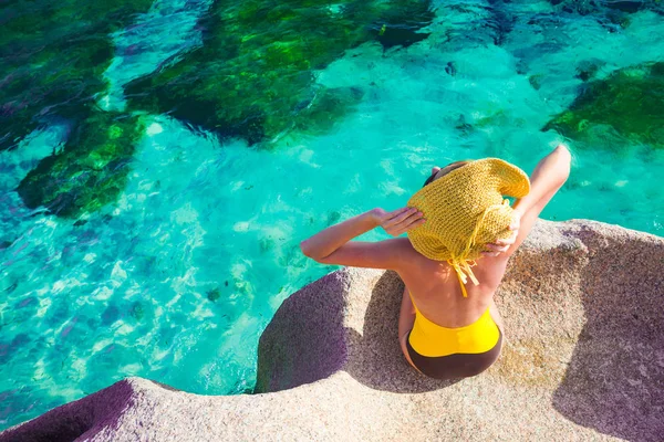 Bella donna in cappello da sole e costume da bagno rilassante sulle rocce sul mare. Seychelles — Foto Stock