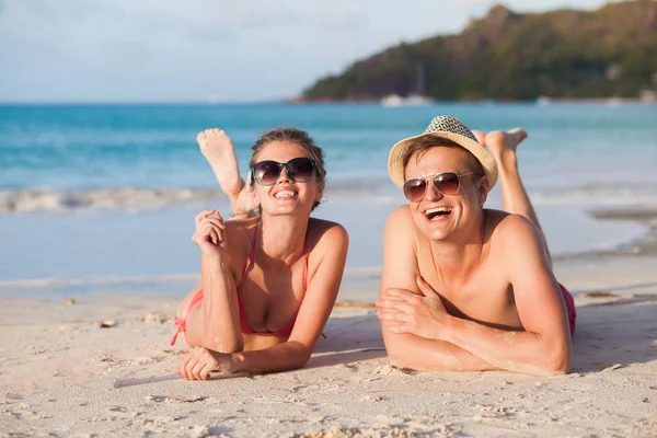 Happy young couple lying and having fun on a tropical beach — Stock Photo, Image