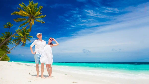 Счастливая молодая пара в белых одеждах веселится на пляже — стоковое фото