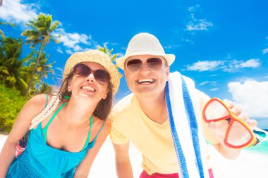 Kumsal aksesuarları olan mutlu genç çift sahilde eğleniyor.