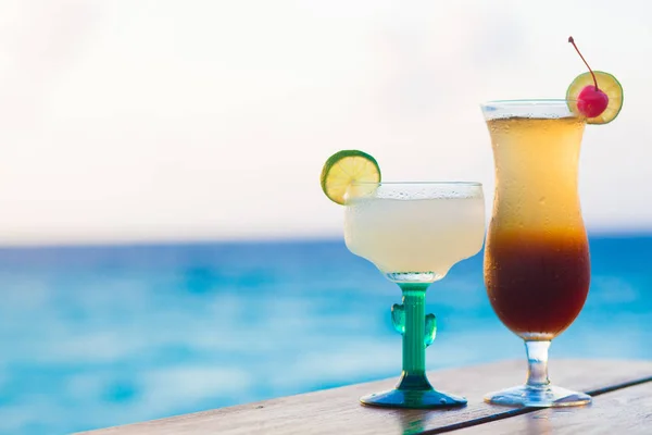 Glass of fruit cocktail and sunglasses by the beach — Stock Photo, Image
