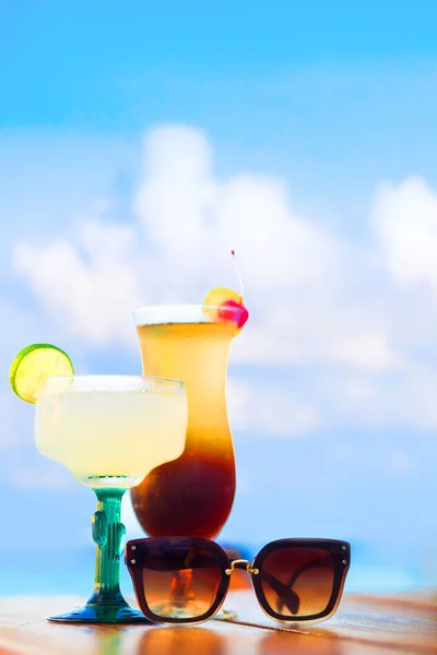 Glass of fruit cocktail and sunglasses by the beach — Stock Photo, Image