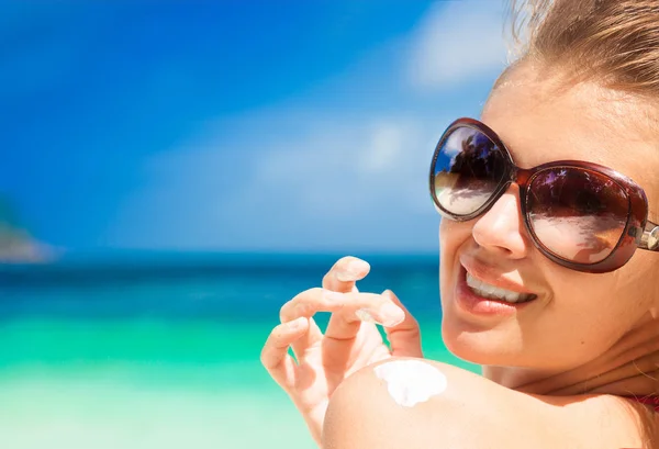 Крупним планом молода жінка в сонцезахисних окулярах кладе сонячний крем на плече — стокове фото