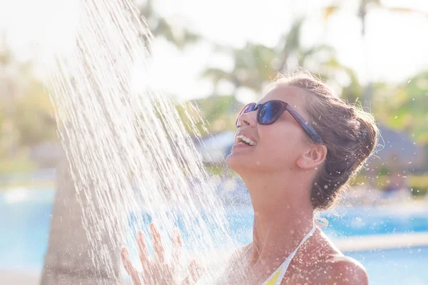 Jonge vrouw verfrissend in douche in de buurt van zwembad — Stockfoto