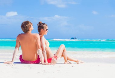 Barbados'taki tropikal bir plajda otururken şapka mutlu genç Çift