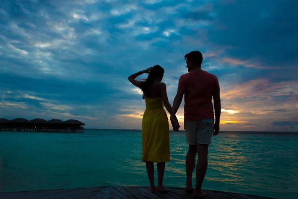Západ slunce silueta mladý pár v lásce objímání na pláži — Stock fotografie