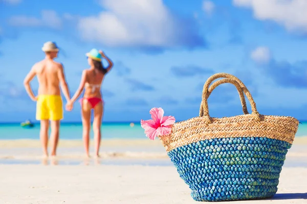 Colorido bolso de playa de paja abd abrazar pareja luna de miel en el fondo —  Fotos de Stock