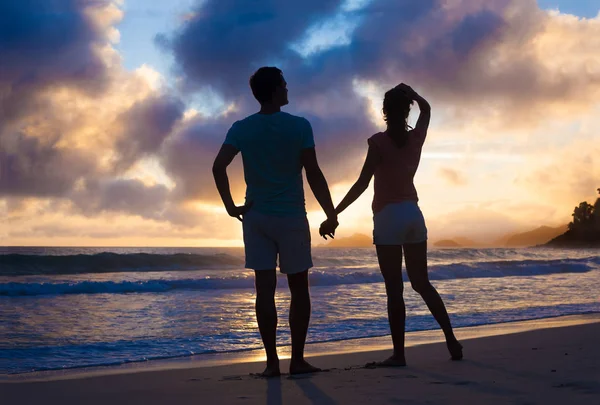 Gün batımı silueti plajda birbirine aşık genç bir çiftin kucaklaşması. — Stok fotoğraf