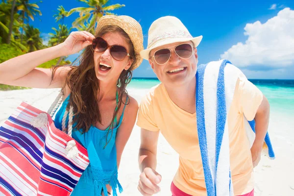 Šťastný mladý pár s plážové doplňky baví u pláže — Stock fotografie