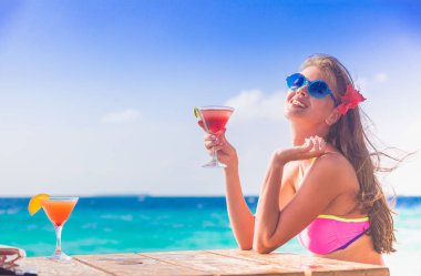 plajda kokteyl ile bikini rahatlatıcı uzun saçlı kadın