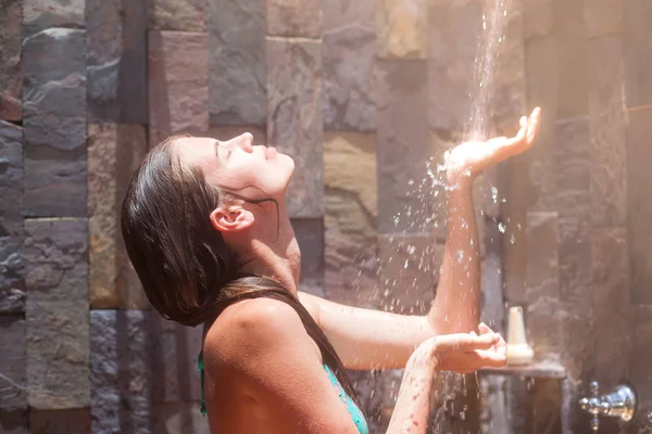 Junge Frau erfrischt sich in tropischer Dusche — Stockfoto