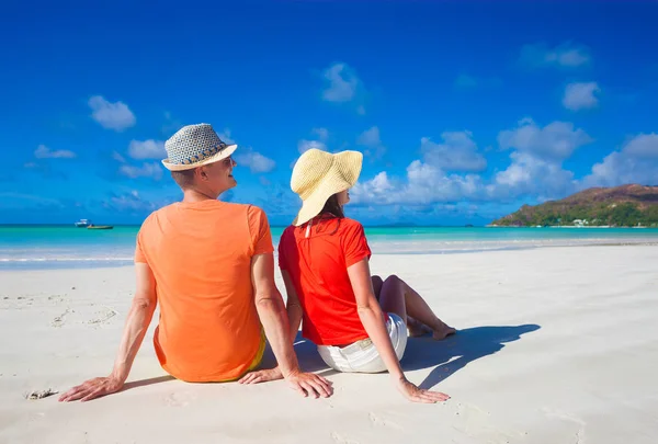 Par i ljusa kläder på en tropisk strand på Praslin, Seychellerna. — Stockfoto