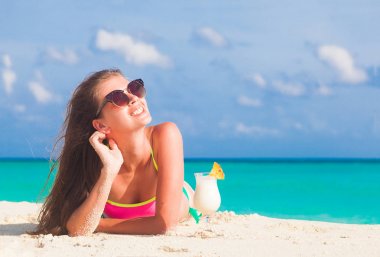 uzun saçlı kadın rahatlatıcı pina colada kokteyli ile beyaz kum plaj, Bikini