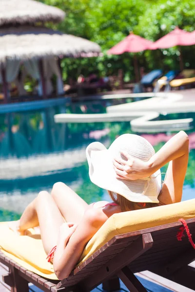 Mujer relajándose en un chaise lounge junto a la piscina de lujo —  Fotos de Stock