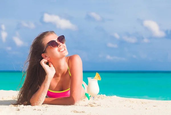 Langhaarige Frau im Bikini entspannt sich am weißen Sandstrand mit Pina-Cola-Cocktail — Stockfoto