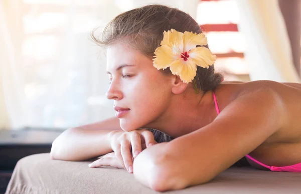 Bela jovem com flor no cabelo aproveitando seu tempo no spa tropical — Fotografia de Stock