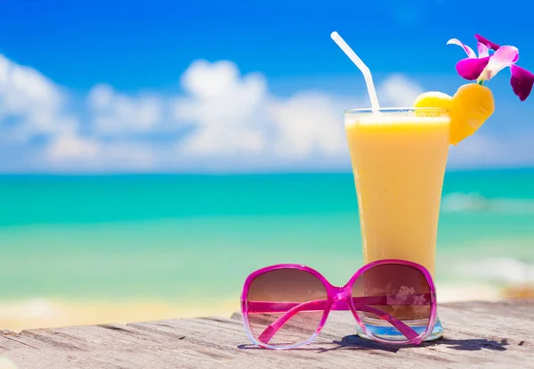 Foto van vers sap van banaan en ananas en zonnebril op tropisch strand — Stockfoto