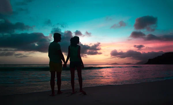 Solnedgång silhuett av unga par i kärlek kramas på stranden — Stockfoto