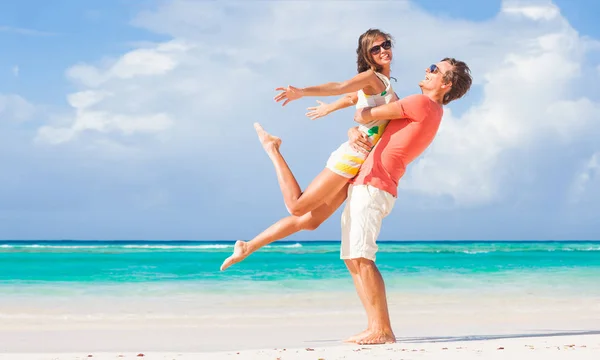 Picture of happy couple in sunglasses hugging on the beach — Stock Photo, Image