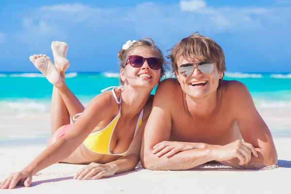 Фотография счастливой пары в солнечных очках, лежащих на пляже — стоковое фото