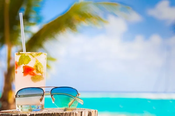 Bicchiere di cocktail freddo mohito e occhiali da sole sul tavolo vicino alla spiaggia — Foto Stock